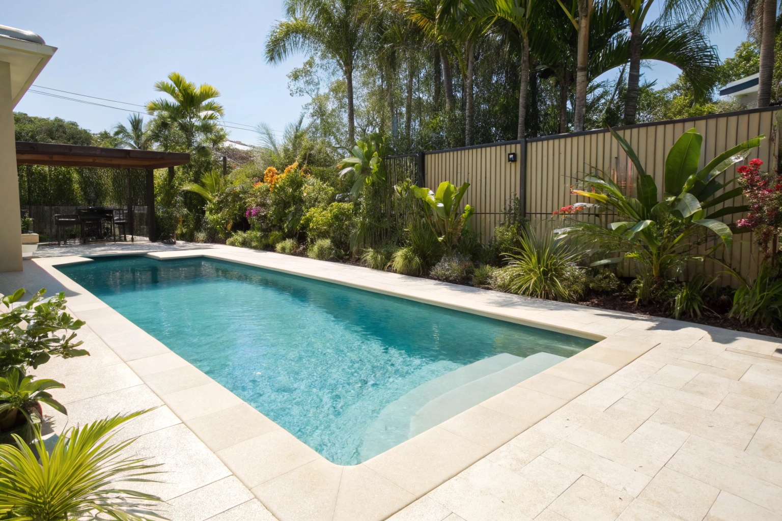 Light coloured concrete pool surround around a backyard pool at a Gold Coast residential property
