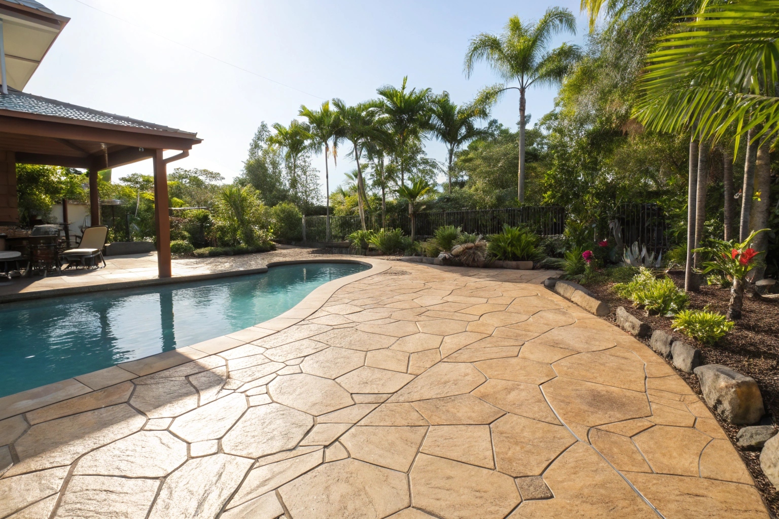 a-wide-stamped-concrete-patio-with-a-warm-sandston Stamped concrete pool surround with flagstone pattern in Gold Coast backyard